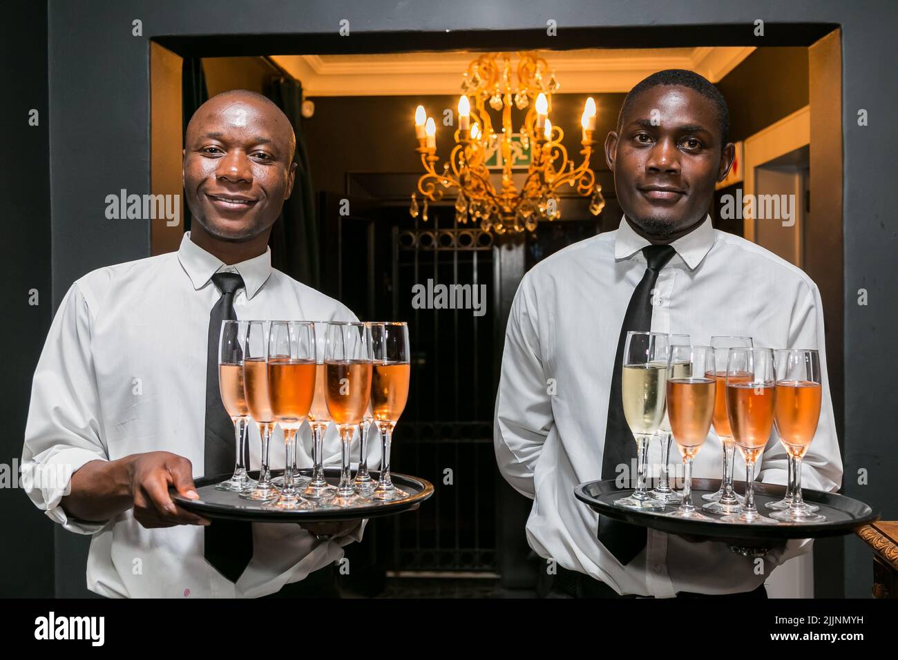 Il personale d'attesa africano con drink di benvenuto su un vassoio al cocktail bar Foto Stock