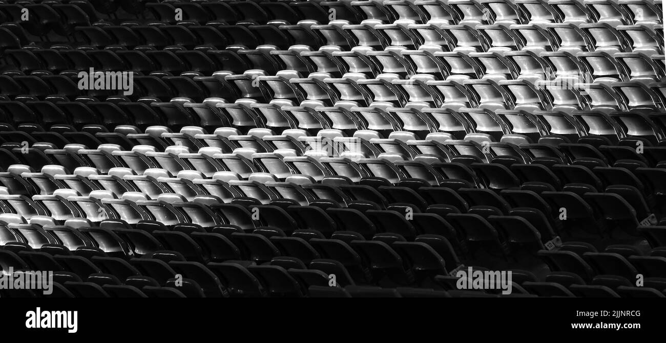 Un'immagine in scala di grigi di un'ombra chiara sui sedili vuoti dello stadio Foto Stock