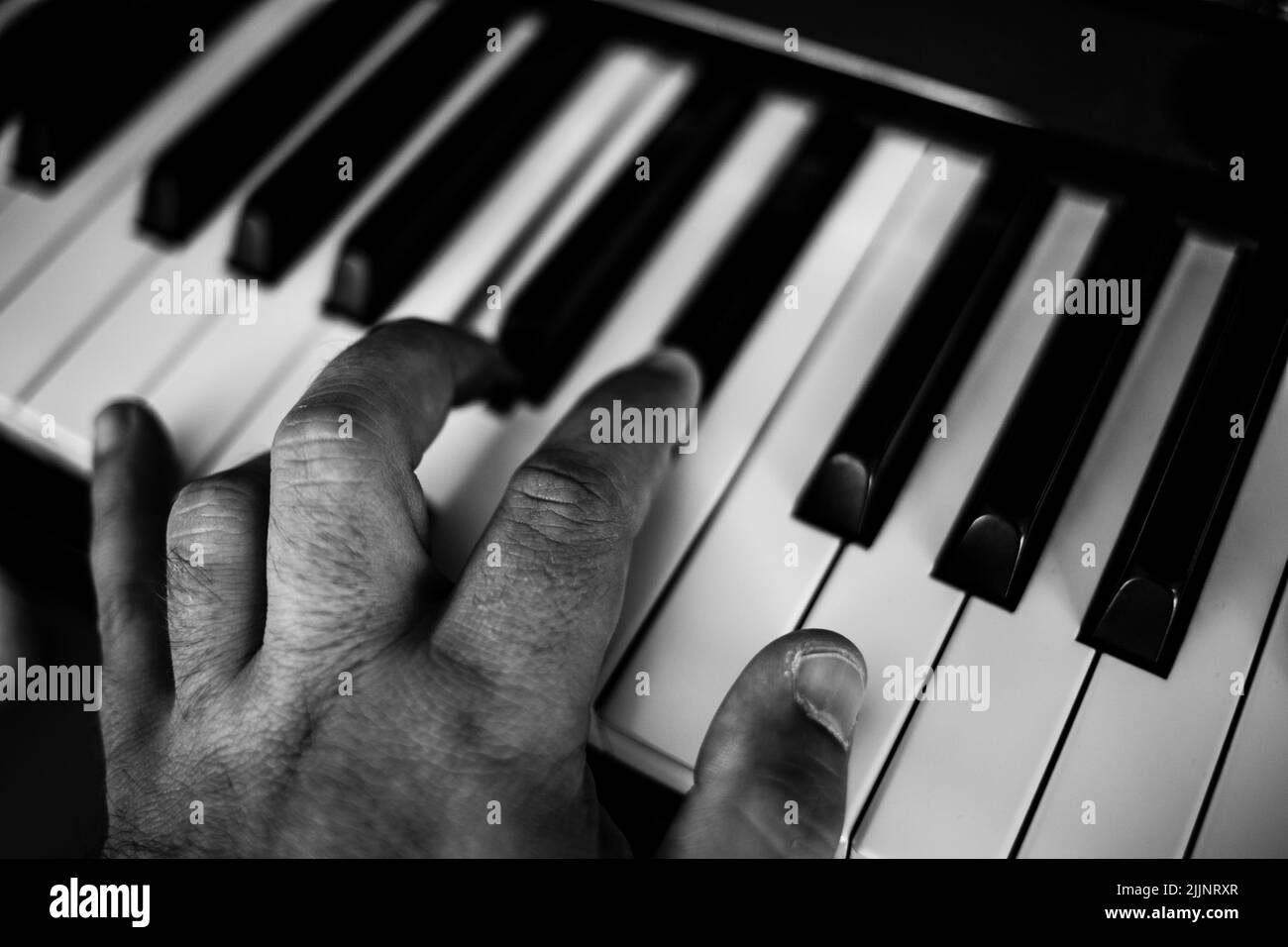 Primo piano in scala di grigi di una mano che suona il pianoforte Foto Stock