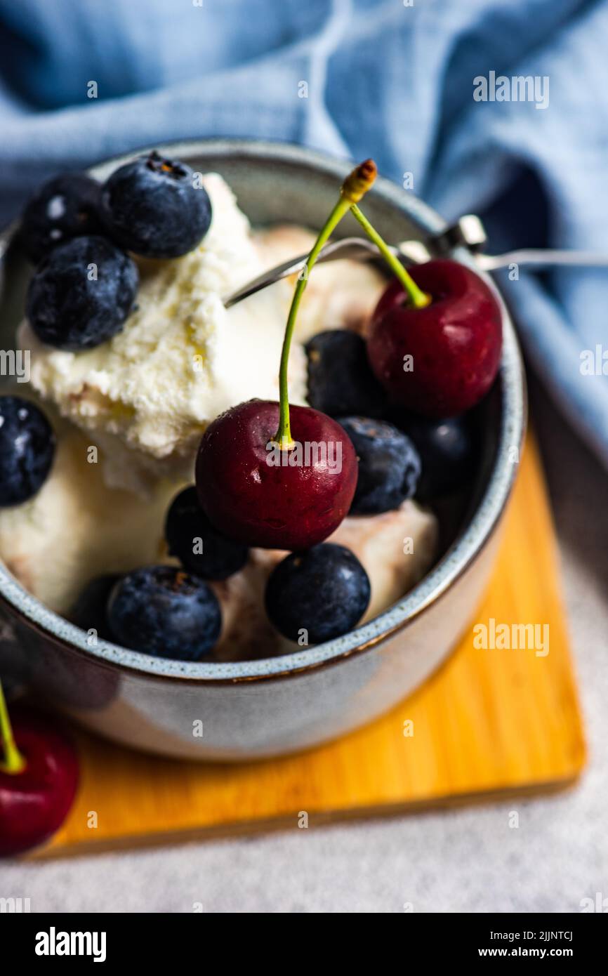 Primo piano di gelato alla vaniglia con mirtilli freschi e ciliegie Foto Stock
