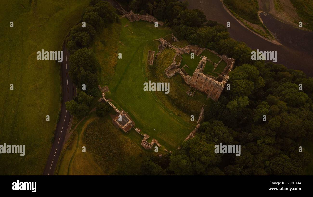 Un'immagine aerea di un vecchio castello circondato da fitti alberi verdi nel Northumberland Foto Stock