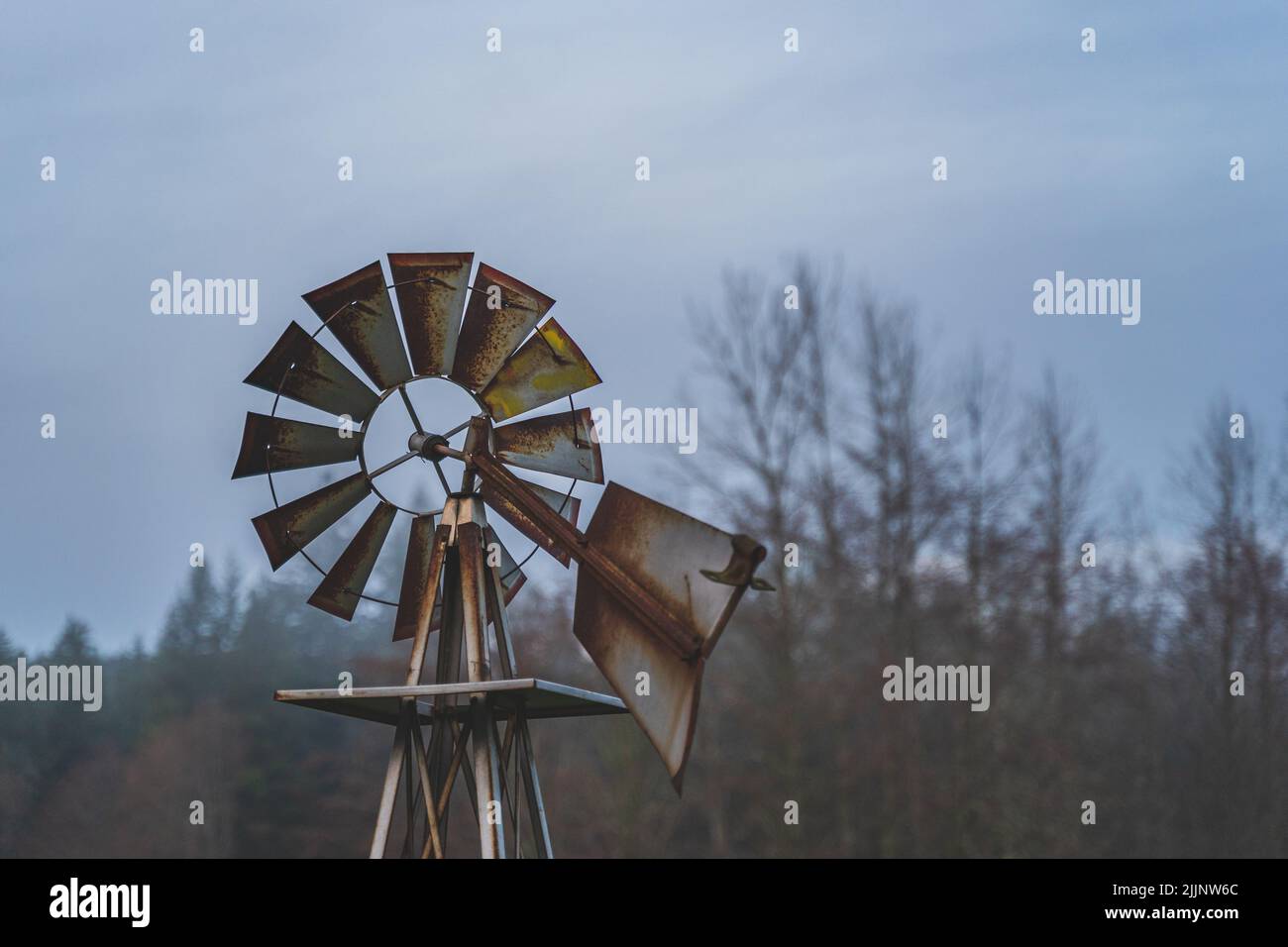 Un angolo basso di un mulino a vento arrugginito contro cielo cupo overcast. Medio colpo incorniciato a destra Foto Stock