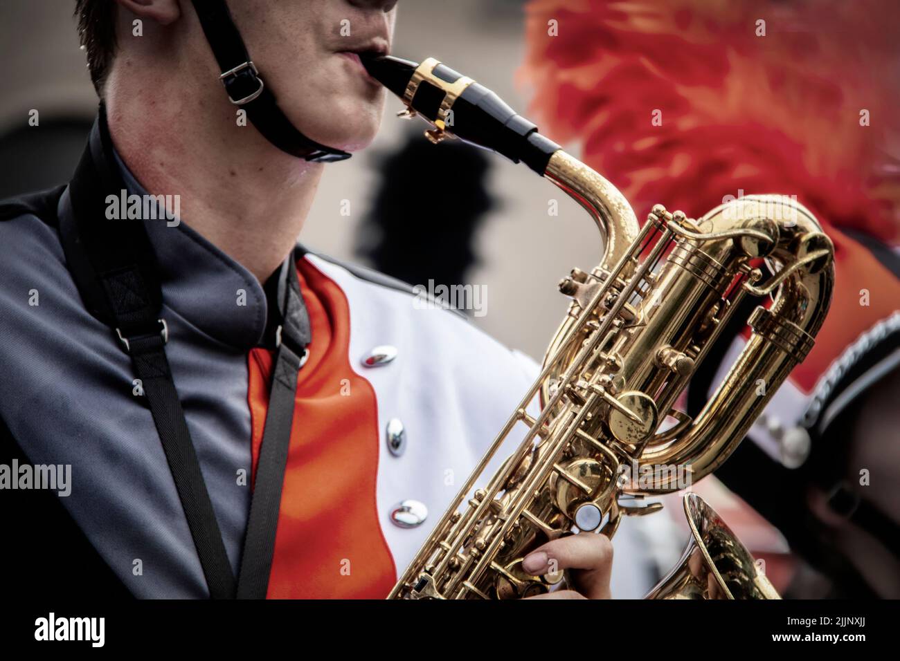 Il musicista della fascia marching maschile in uniforme suona la tromba - Closeup e cropped - cinghia del cappello sotto il mento Foto Stock