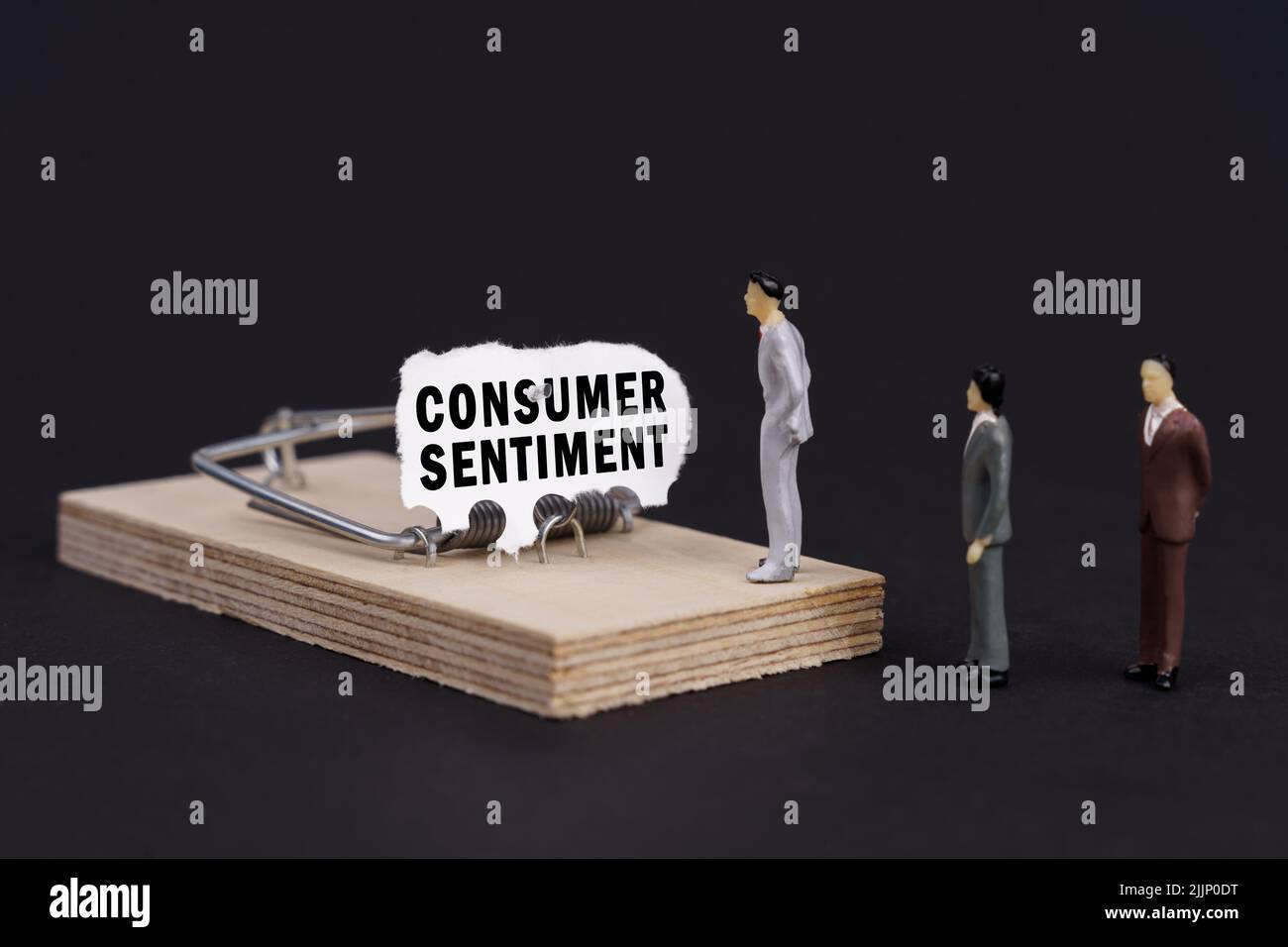 Trappola aziendale, concetto di crisi. Figure di uomini d'affari si trovano vicino a un mousetrap, l'esca in cui è strappato carta con l'iscrizione - Consumer Sennimen Foto Stock