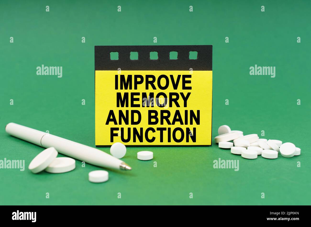Concetto medico. Sulla superficie verde sono le compresse, una penna e gli adesivi con l'iscrizione - migliorare la memoria e la funzione cerebrale Foto Stock