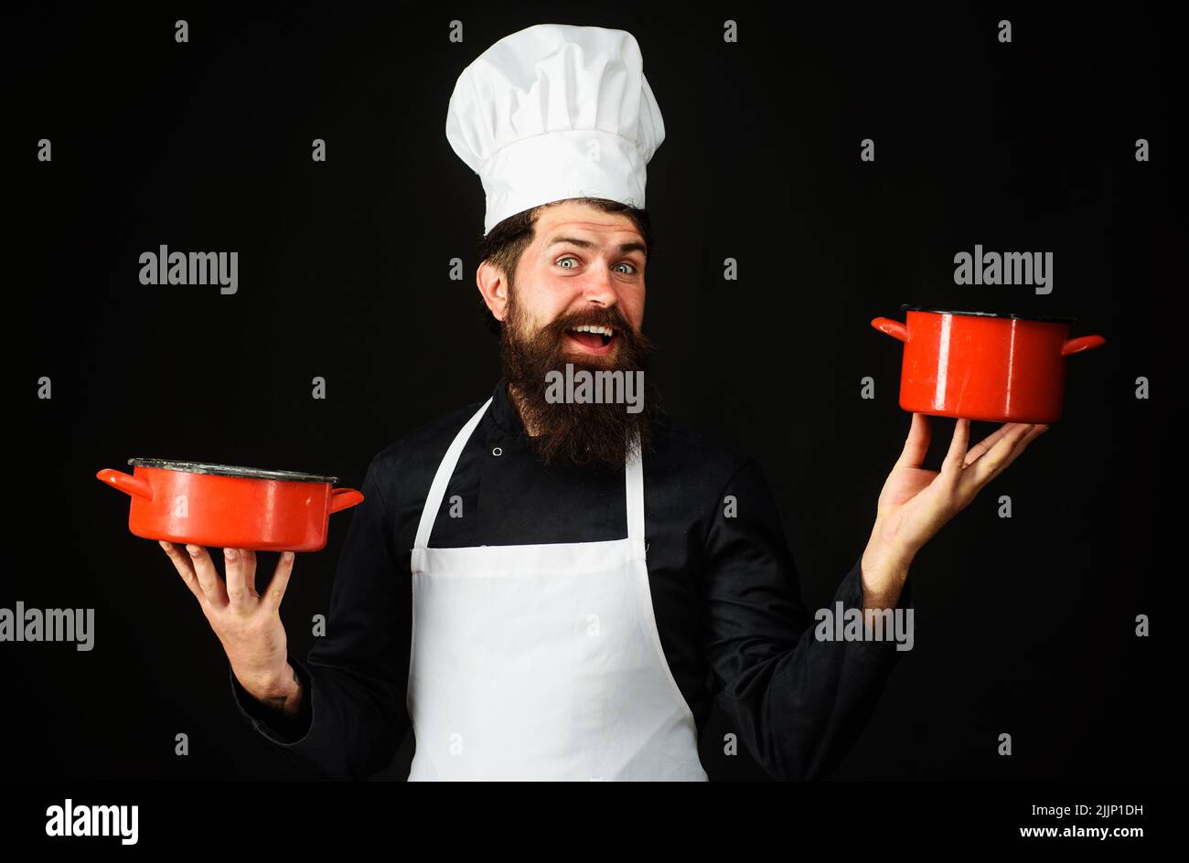 Chef sorridente in uniforme con pentole. Cuoco maschile in grembiule bianco e cappello con pentole. Cucina cibo. Foto Stock