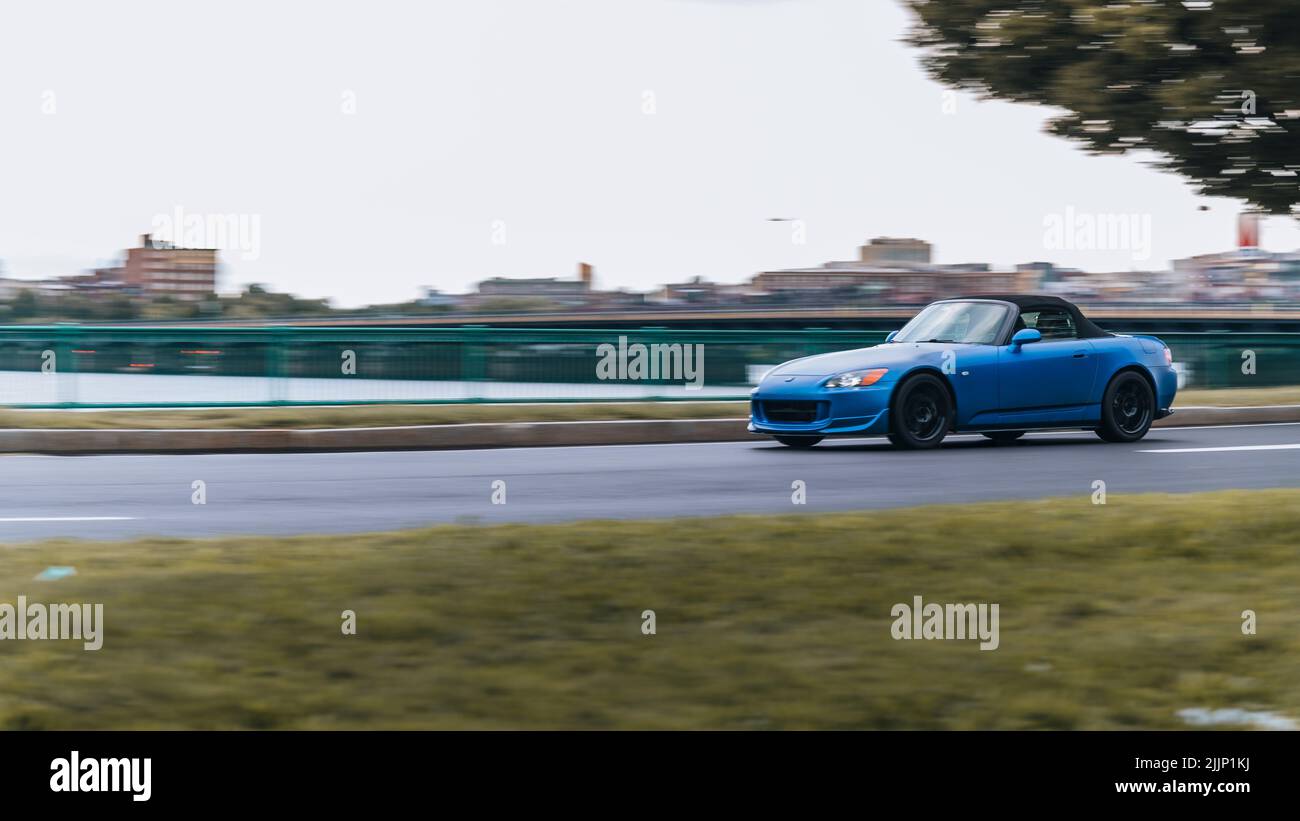 Shot di auto Blue che guida veloce di fronte allo skyline di Boston Foto Stock