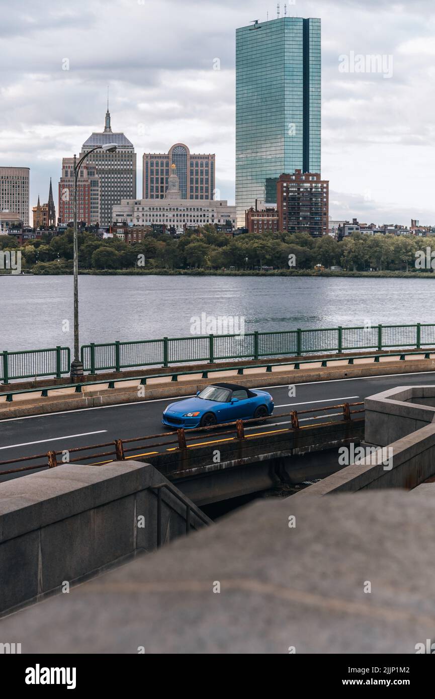 Scatto verticale di auto blu che guida di fronte allo skyline della città di Boston. Foto Stock