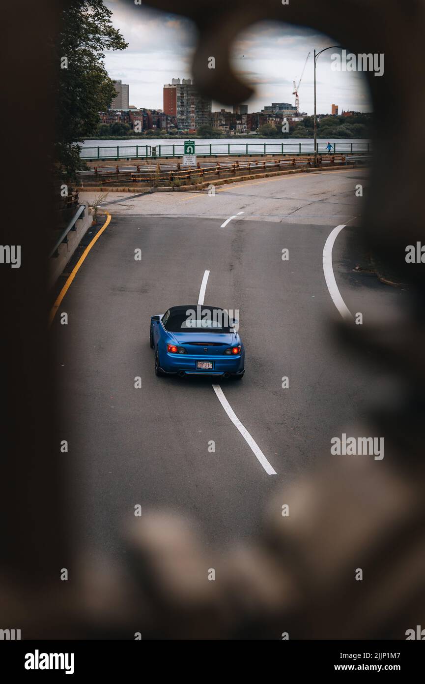 Colpo verticale di auto Blue che guida velocemente di fronte allo skyline di Boston Foto Stock
