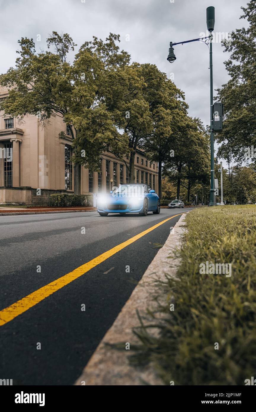 Colpo verticale di auto Blue che guida velocemente di fronte allo skyline di Boston Foto Stock