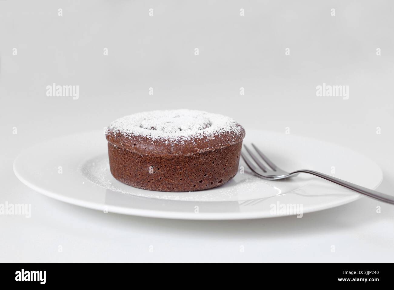 Torta al cioccolato fondente con zucchero a velo e fondo bianco Foto Stock