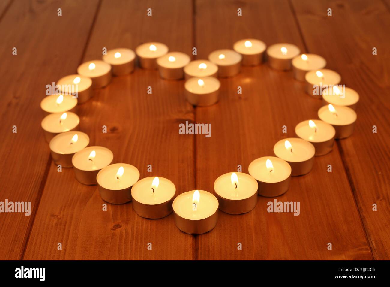 Piccole candele che fanno un cuore sul tavolo o sul pavimento di legno - serata romantica Foto Stock