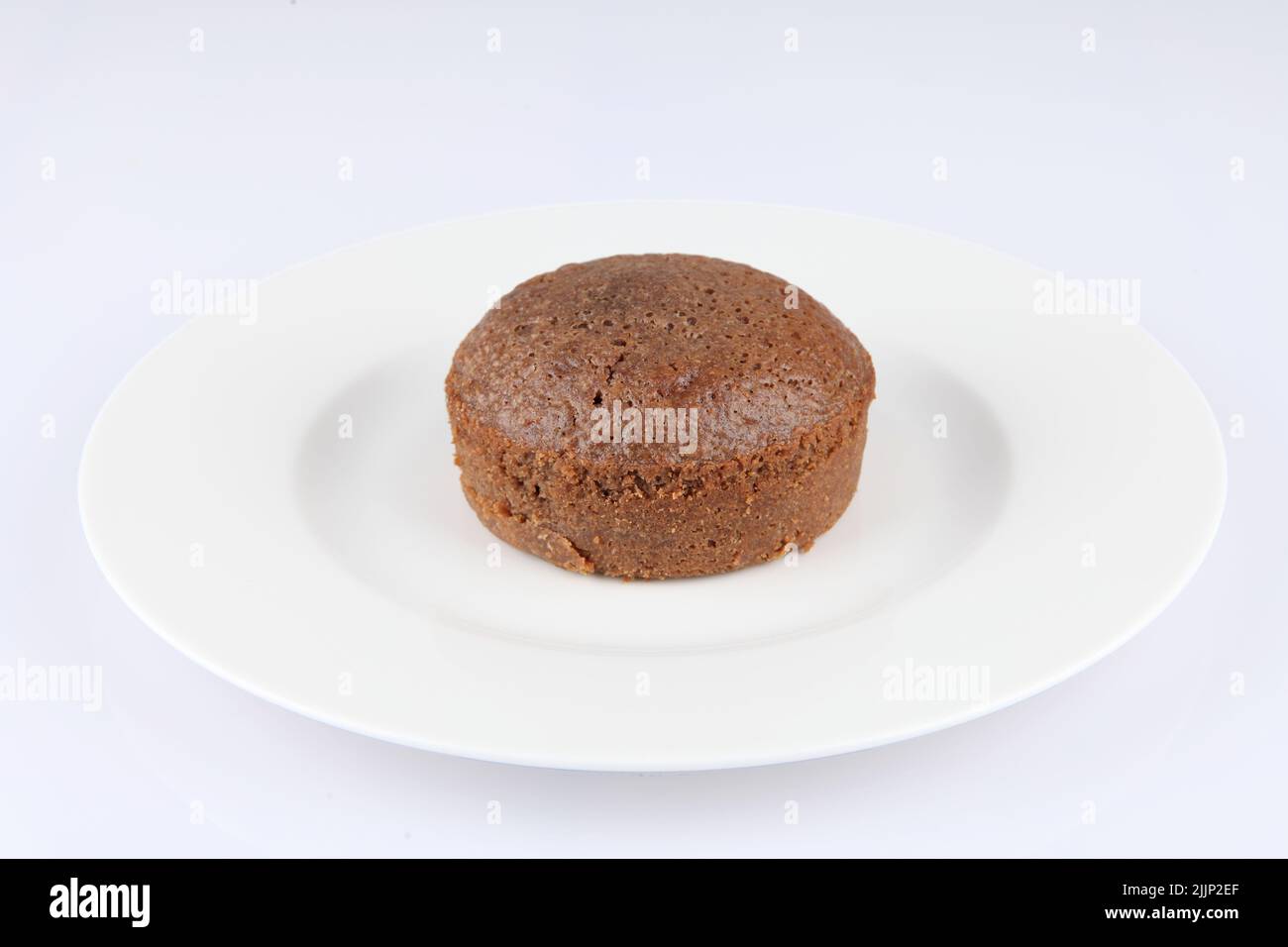 Un souffle di cioccolato in un classico ramekin porcellana bianca su un piatto bianco Foto Stock