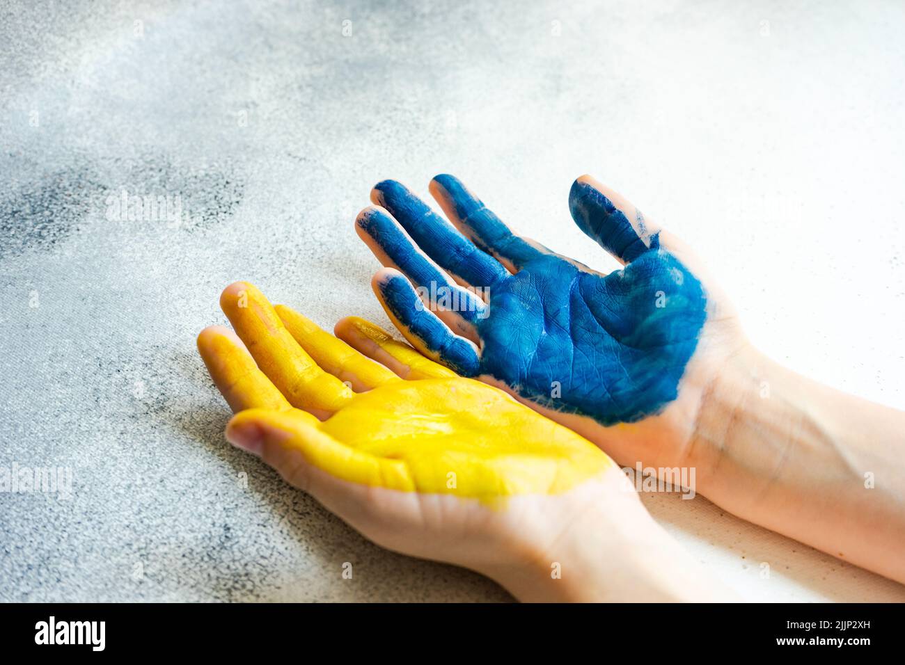 Primo piano delle mani di una persona dipinte di giallo e blu per simboleggiare il sostegno dell'Ucraina Foto Stock