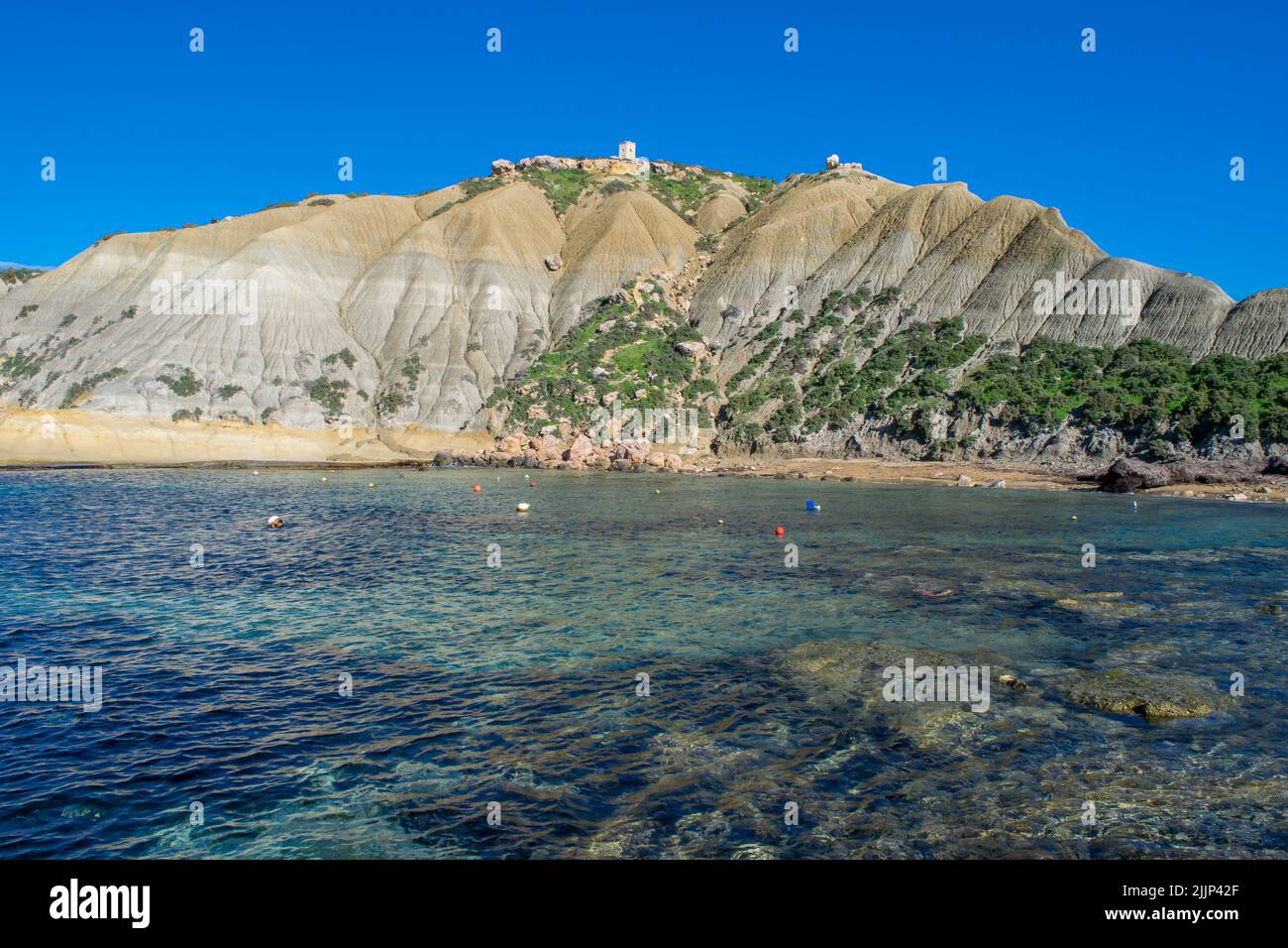 Ripidi pendii di argilla blu, con detriti scaglianti che formano un calcare lungo la costa di Xatt l-Ahmar, Ghajnsielem, Gozo, Malta, in una giornata di sole. Foto Stock