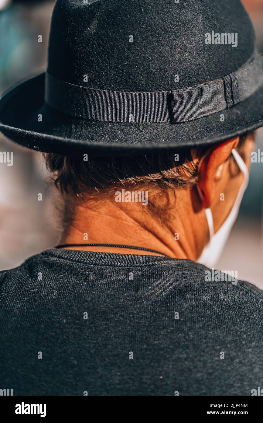 Un primo piano di un vecchio uomo con un cappello in piedi davanti ai dipinti su uno sfondo sfocato Foto Stock