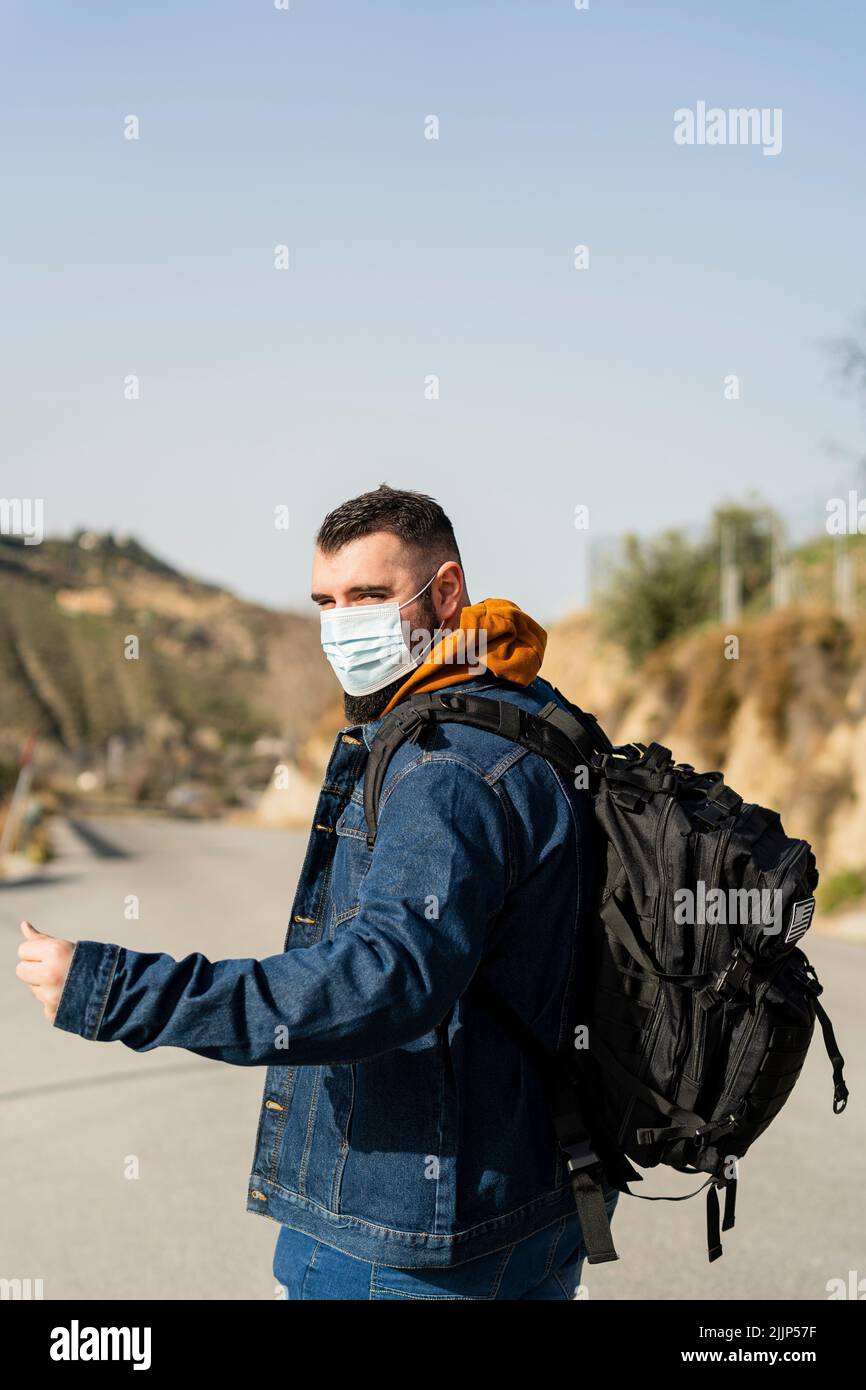 Un colpo di uomo caucasico che indossa la maschera e fa hitchhiking Foto Stock