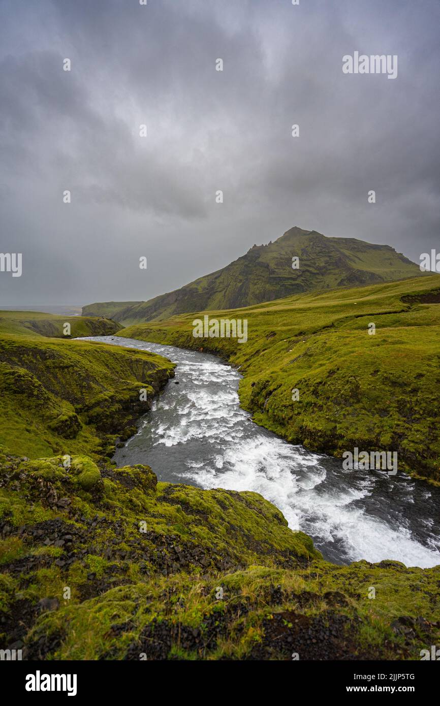 Un colpo verticale di uno stretto torrente d'acqua che scorre lungo la valle verde in montagna Foto Stock