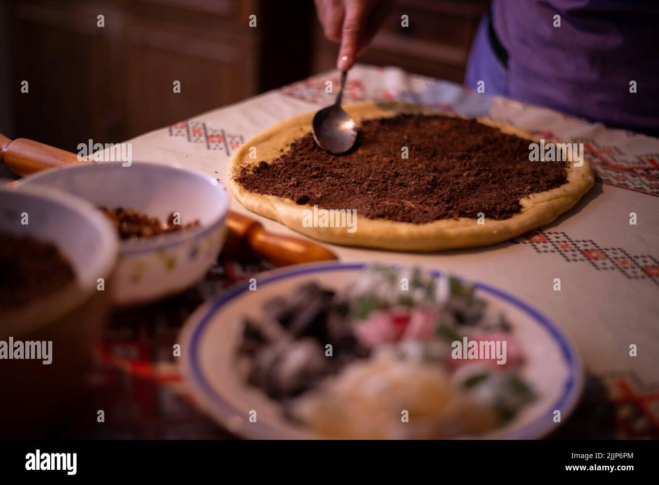 Una casalinga che aggiunge il ripieno all'impasto Foto Stock