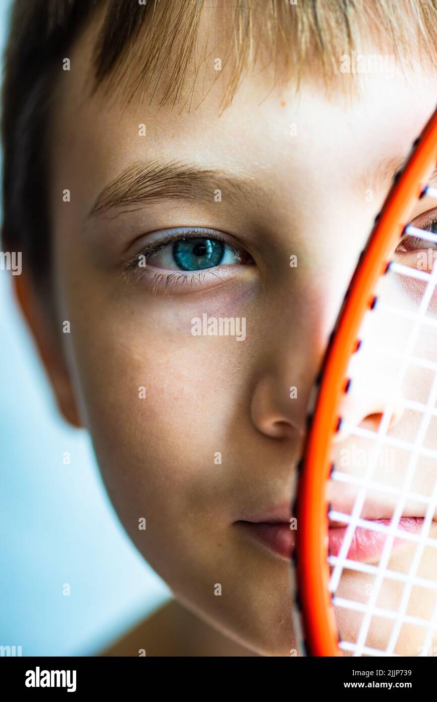 Ragazzo che tiene una racchetta da tennis davanti al viso Foto Stock