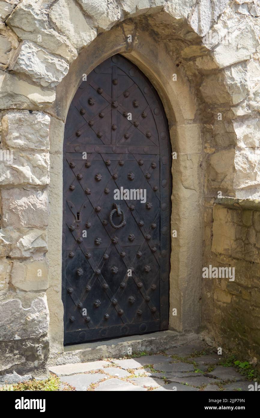 La porta alla torre del castello. Le mura del castello. Porte rivestite in lamiera e inchiodate con perni in acciaio Foto Stock