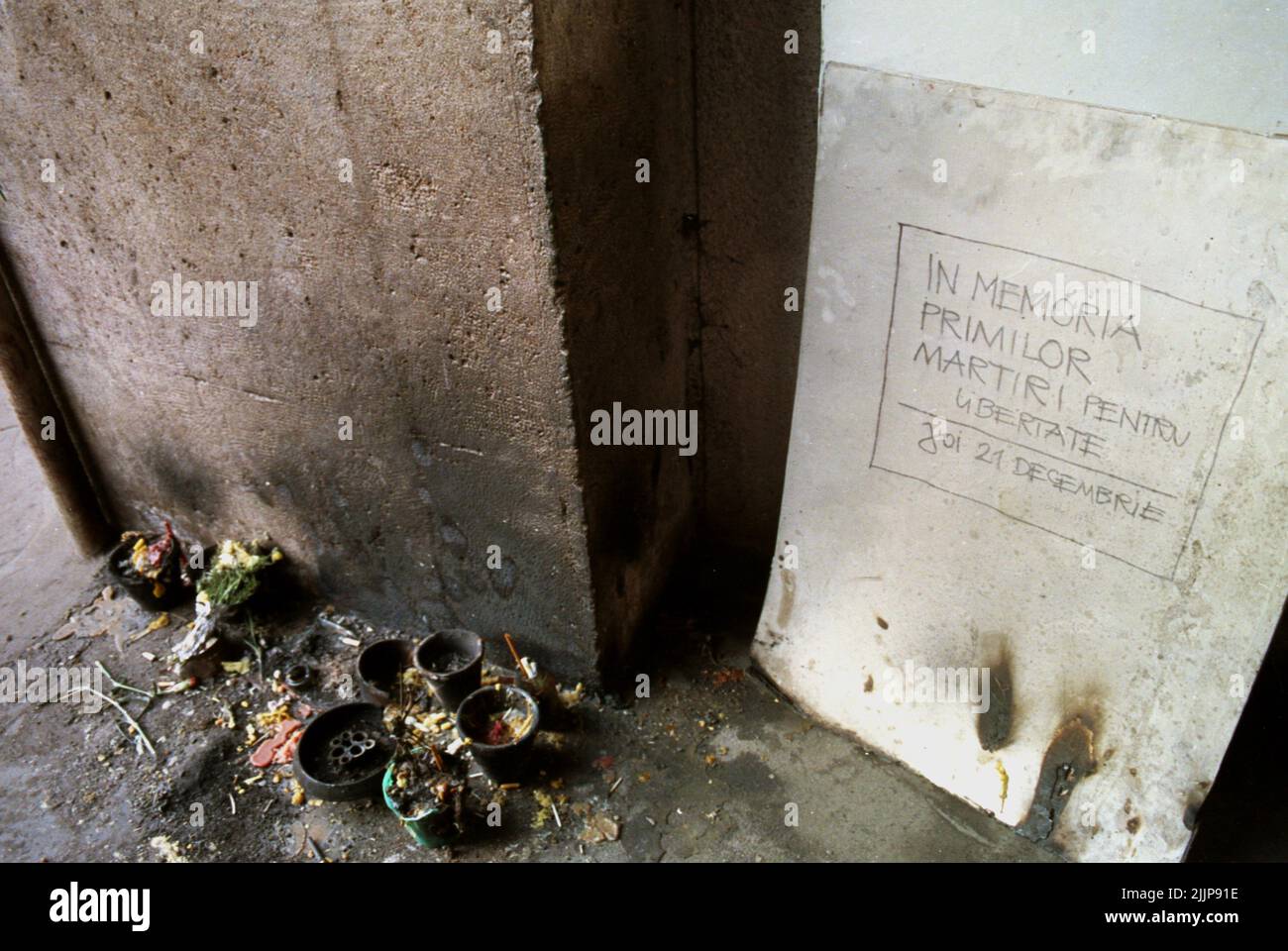 Bucarest, Romania, gennaio 1990. Piccolo memoriale di fronte alla Sala Dalles per le prime vittime della rivoluzione romena anticomunista del dicembre 1989. A terra, la gente sta bruciando le candele. Sul muro è scritto 'in memoria dei primi martiri per la libertà. Giovedì 21 dicembre. La morte delle prime sette vittime della rivolta è stata causata da un camion militare che ha colpito i manifestanti. Foto Stock