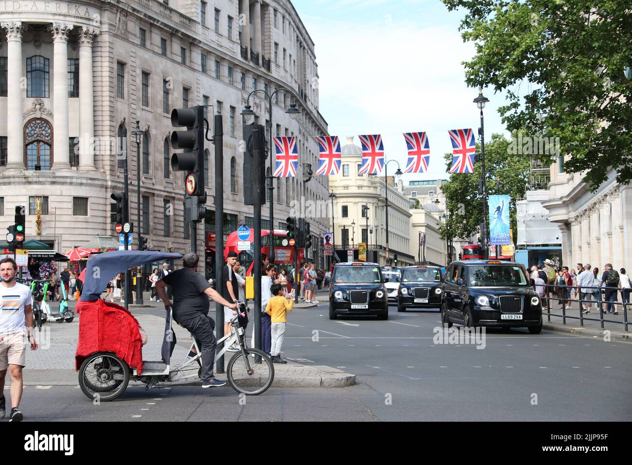 TAXI NERI DI LONDRA PASSANDO DA STRAND A PIAZZA TRAFALGER A LONDRA Foto Stock
