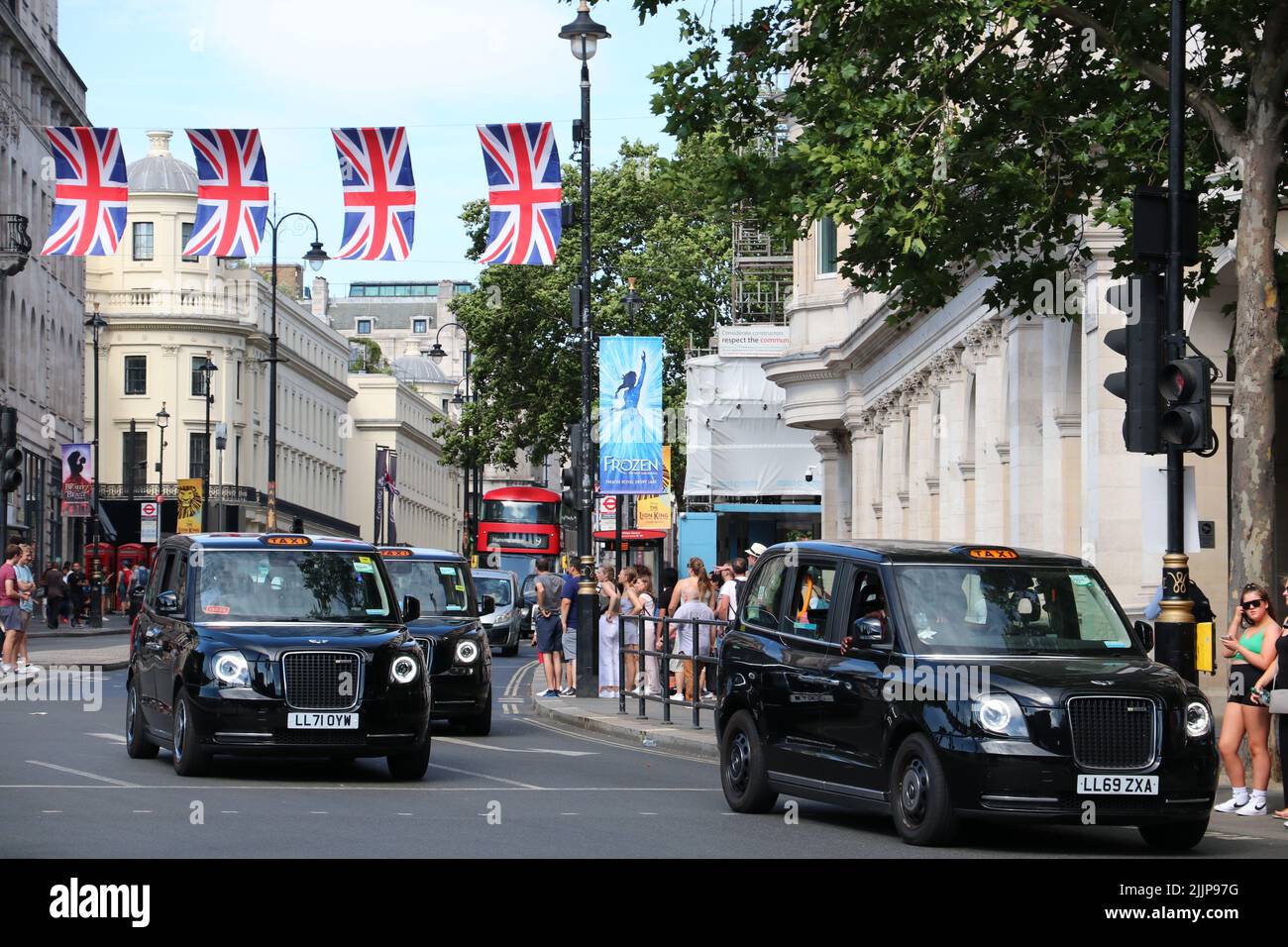 TAXI NERI DI LONDRA PASSANDO DA STRAND A PIAZZA TRAFALGER A LONDRA Foto Stock