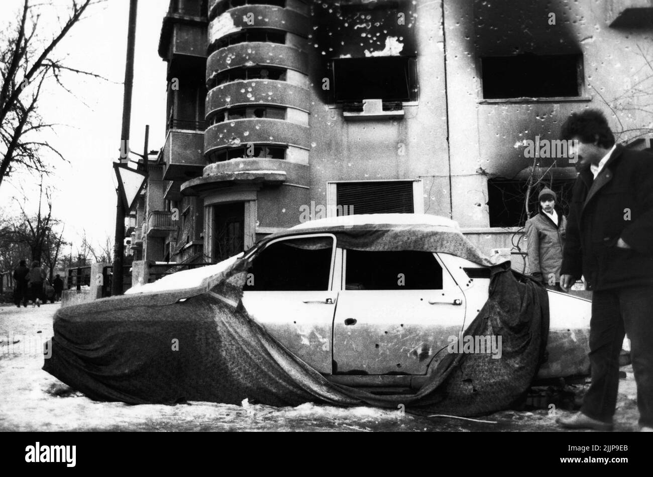 Bucarest, Romania, gennaio 1990. Edifici residenziali nel centro storico e veicolo deteriorati dal fuoco durante la rivoluzione romena anticomunista del dicembre 1989. Foto Stock