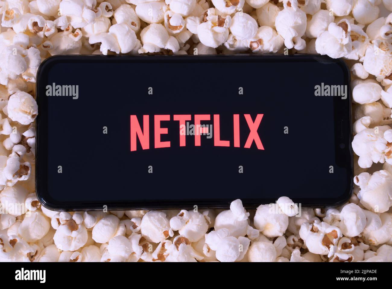A preparare il popcorn per guardare un film su Netflix con il telefono cellulare Foto Stock