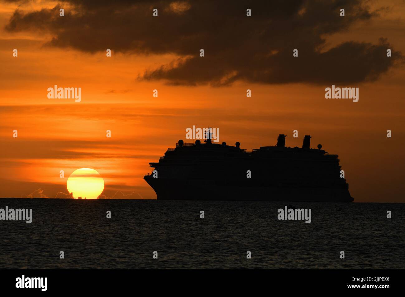 silhouette di uno yacht contro uno splendido tramonto arancione Foto Stock