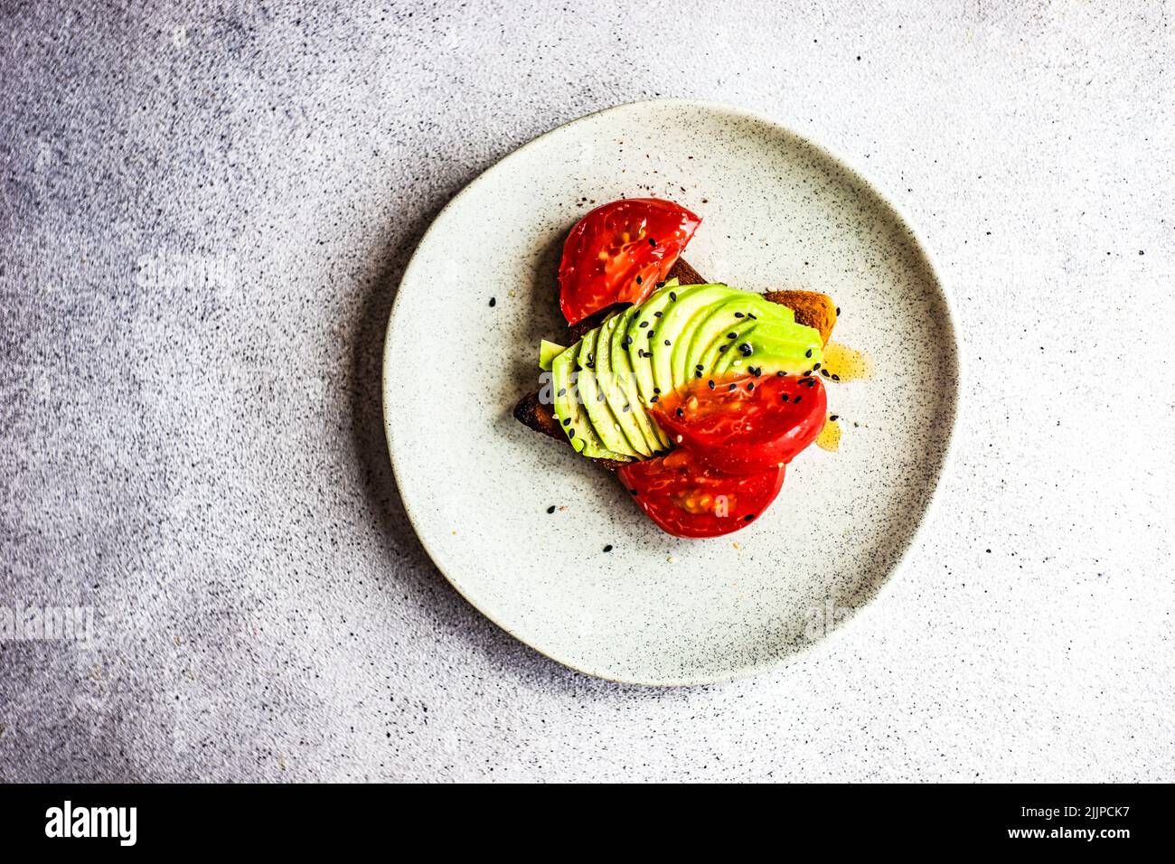 Vista dall'alto di una fetta di toast avocado con pomodori e semi di sesamo Foto Stock