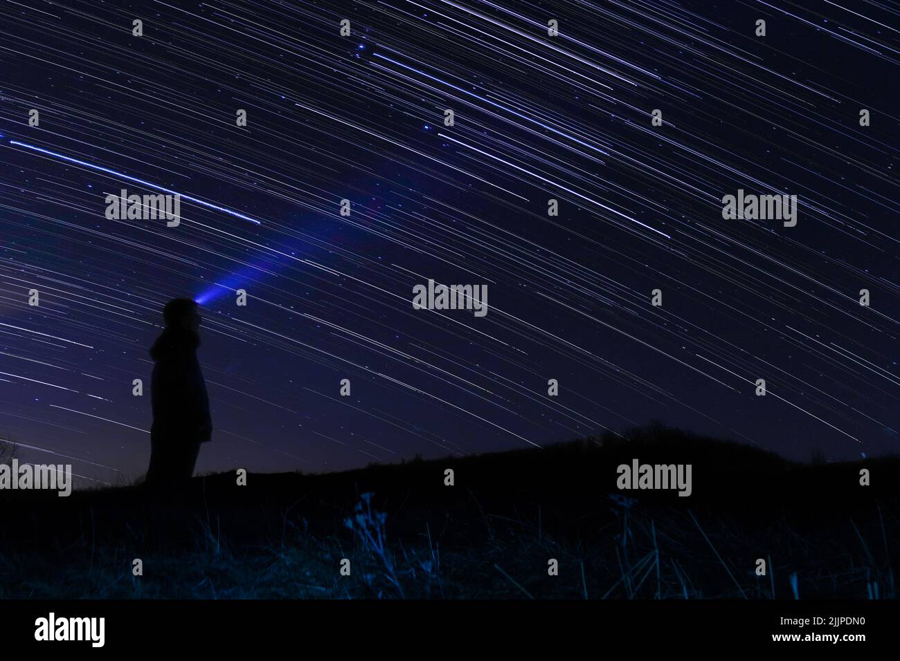 Una persona con una torcia che guarda i sentieri stellari di notte Foto Stock