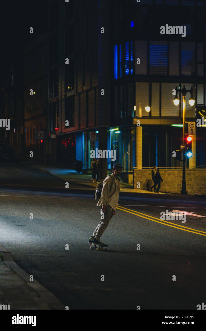 Un colpo verticale di un ragazzo pattinare di notte sulla strada in Quebec, Canada Foto Stock