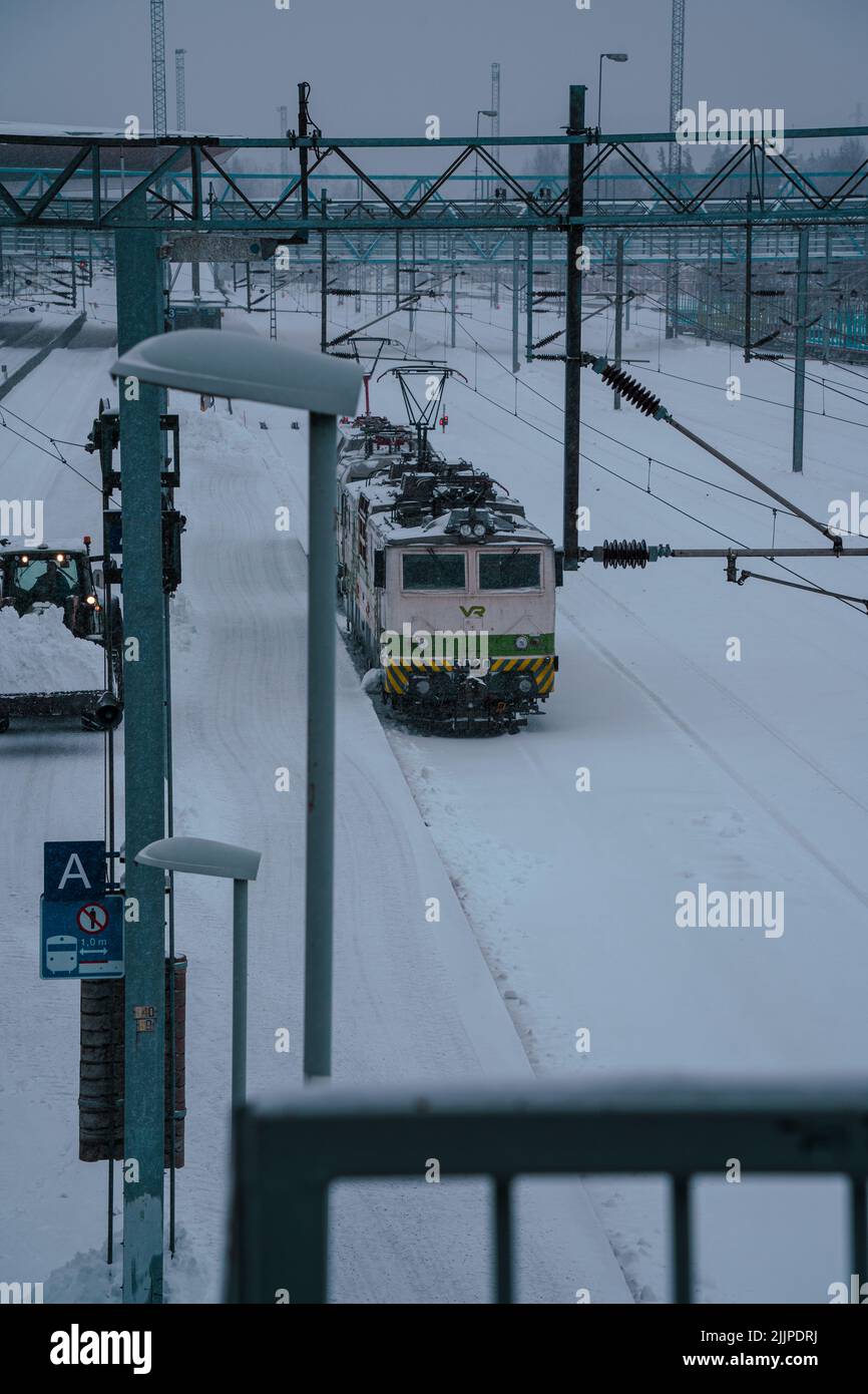 Uno scatto verticale di un treno in attesa alla stazione tutto coperto di neve a Jarvenpaa, Finlandia Foto Stock