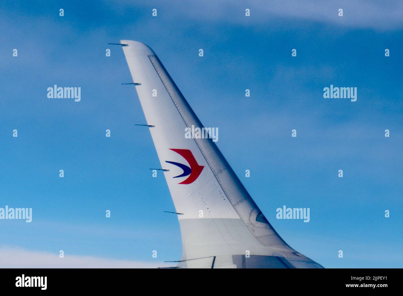 Un colpo laterale di un'ala dell'aereo della Cina orientale con nuvoloso blu sullo sfondo Foto Stock