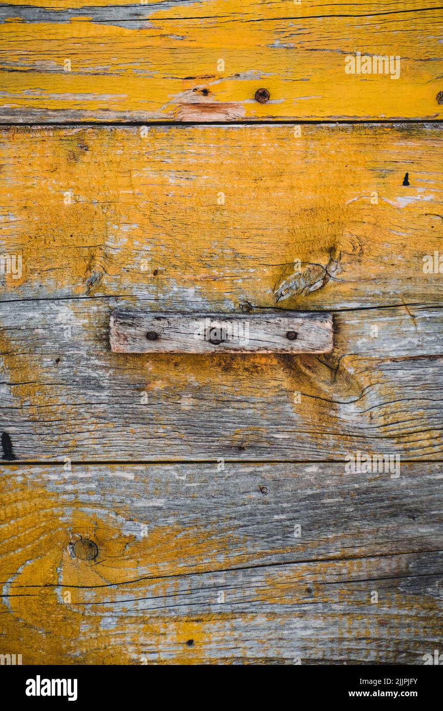 Un colpo verticale di una superficie di legno intemperiato con vernice gialla Foto Stock