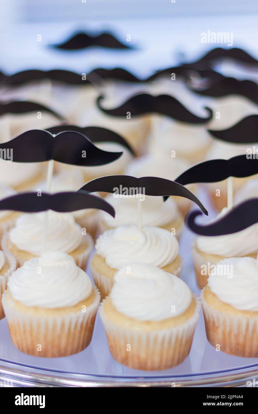 Piccoli cupcake con glassa bianca sulla parte superiore e baffi decorazione per i ragazzi festa di compleanno Foto Stock