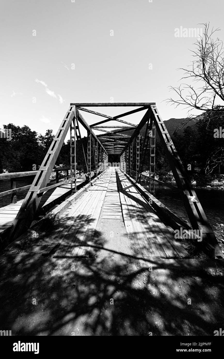 Un'immagine in scala di grigi di un lungo ponte sospeso in una giornata di sole Foto Stock
