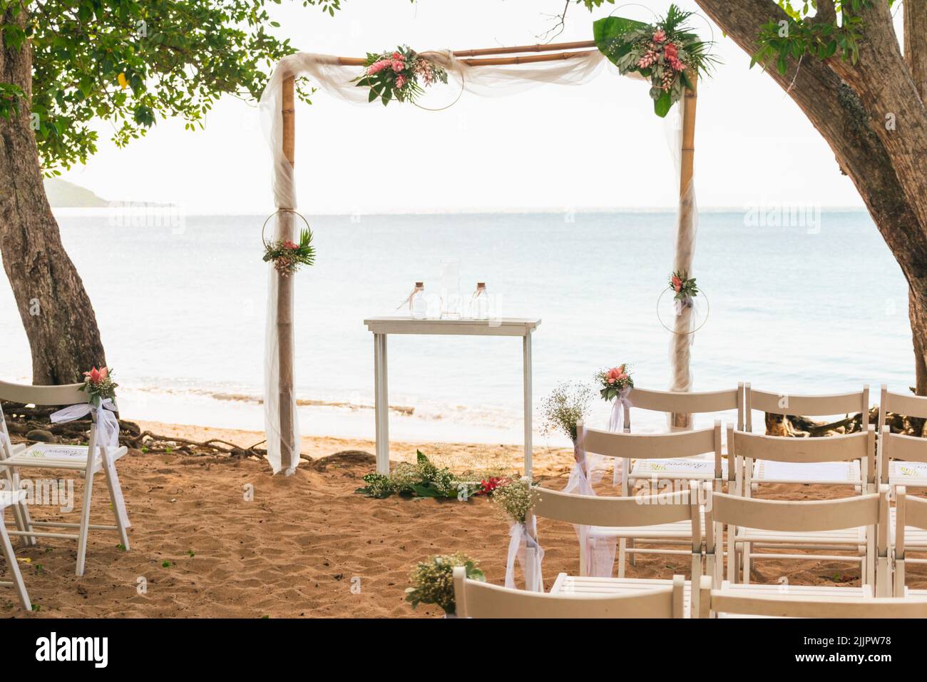 Un semplice matrimonio sulla spiaggia allestito accanto ad un albero sul mare Foto Stock