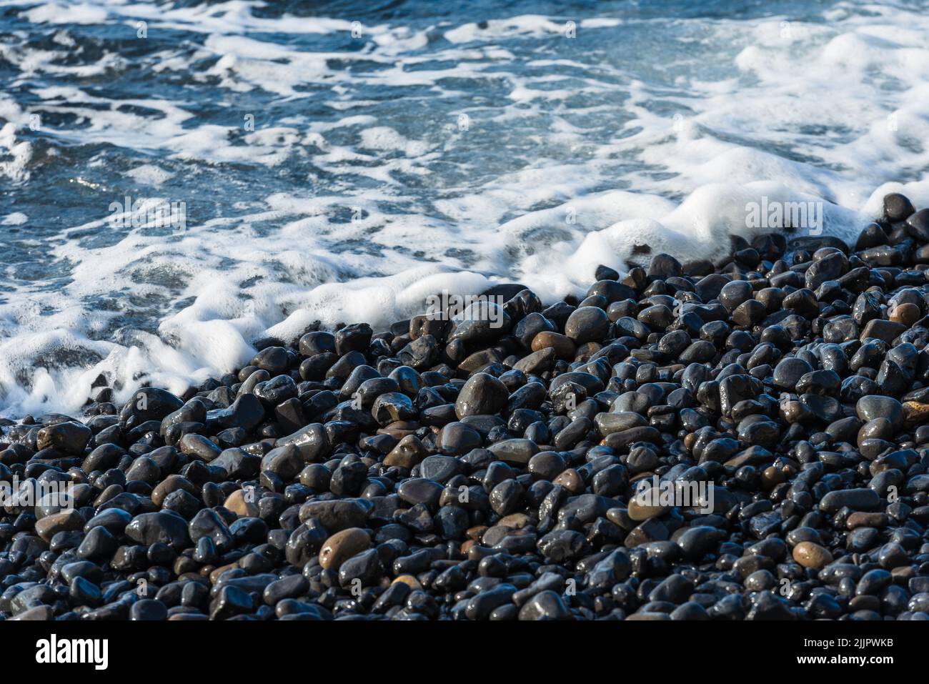 Onde che si infrangono sui ciottoli vulcanici neri della spiaggia di Mavra volta sull'isola di Chios in Grecia. Foto Stock