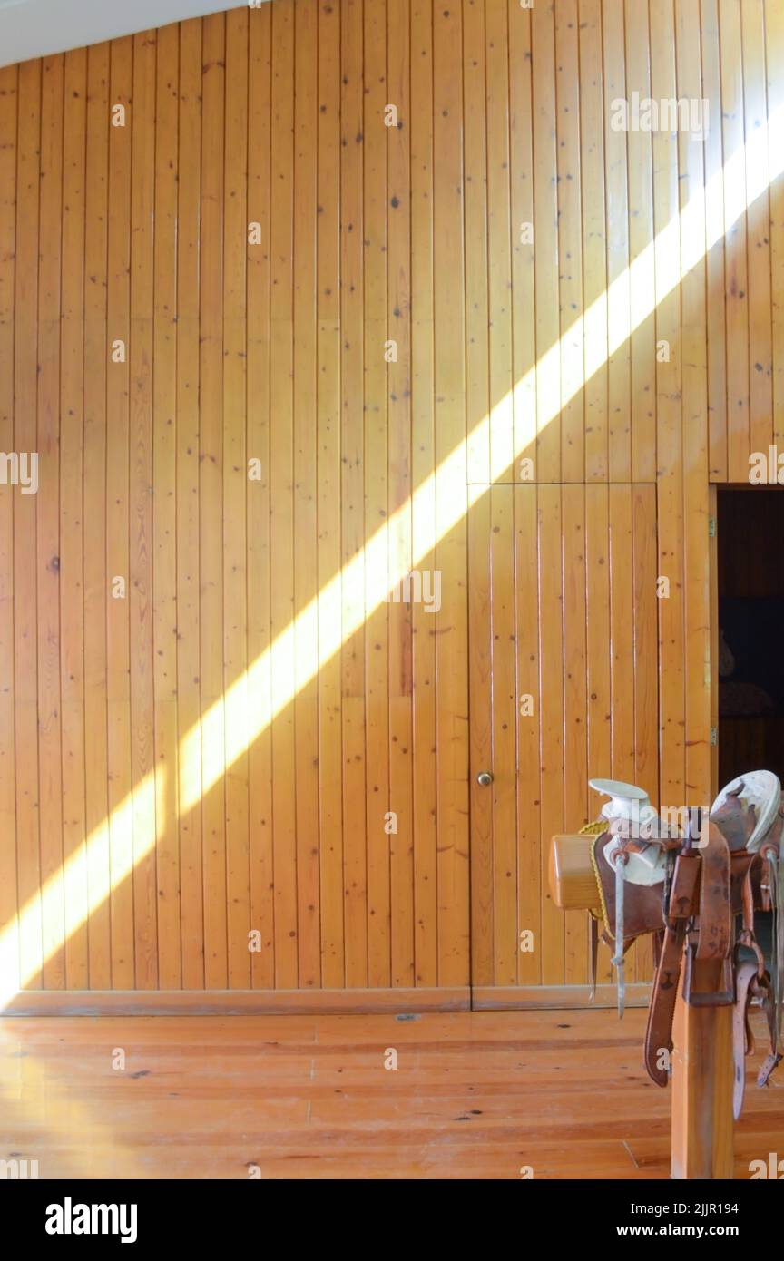 La luce del sole entra attraverso una finestra e getta ombre quadrate contro il pavimento di legno. Foto Stock