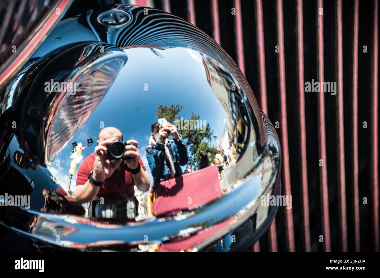 Il riflesso di un padre e di un figlio che scattano foto di auto d'epoca su una superficie riflettente Foto Stock