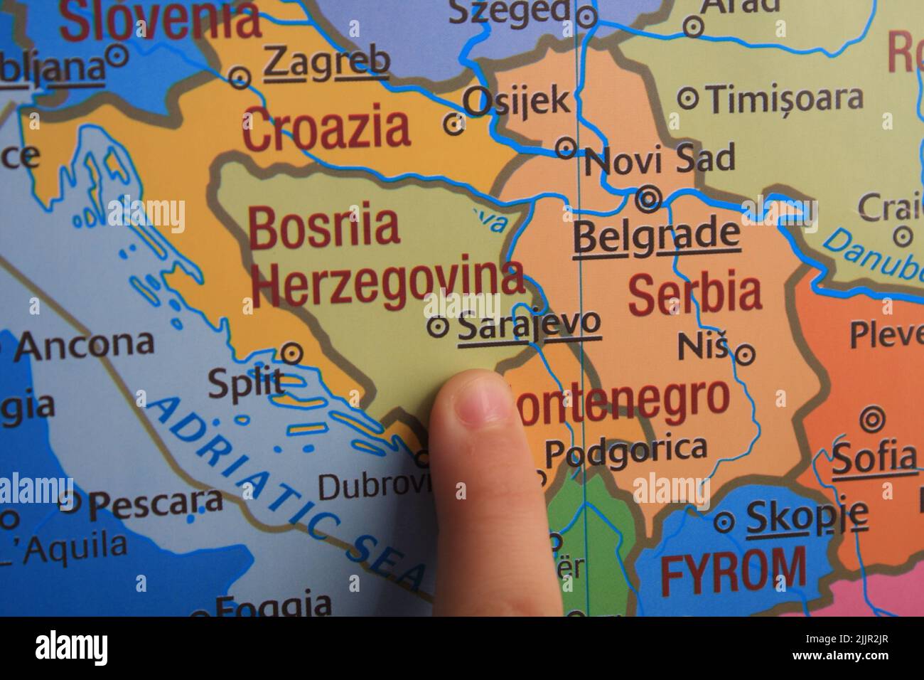 Primo piano di un dito che punta alla Bosnia-Erzegovina su una mappa del mondo Foto Stock