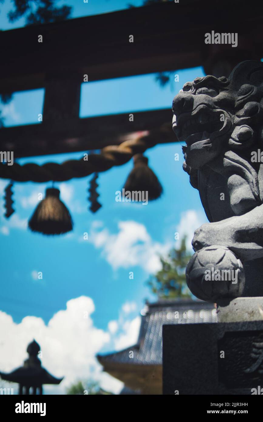 Un colpo verticale di un santuario estivo giapponese con un komainu Foto Stock