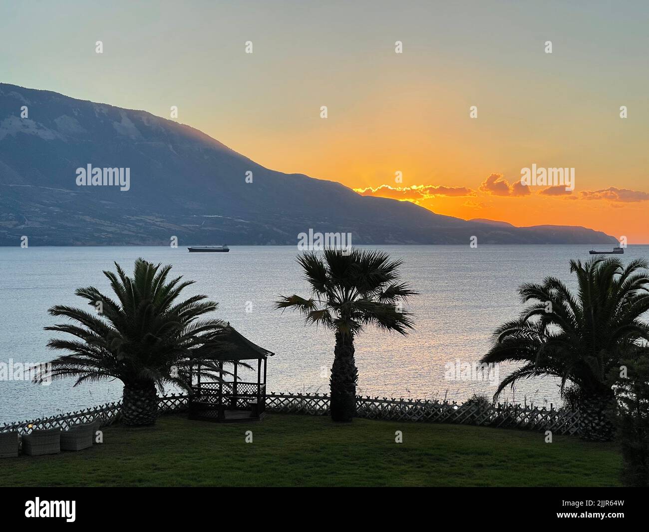 Una bella vista delle palme su una spiaggia durante un tramonto arancione Foto Stock