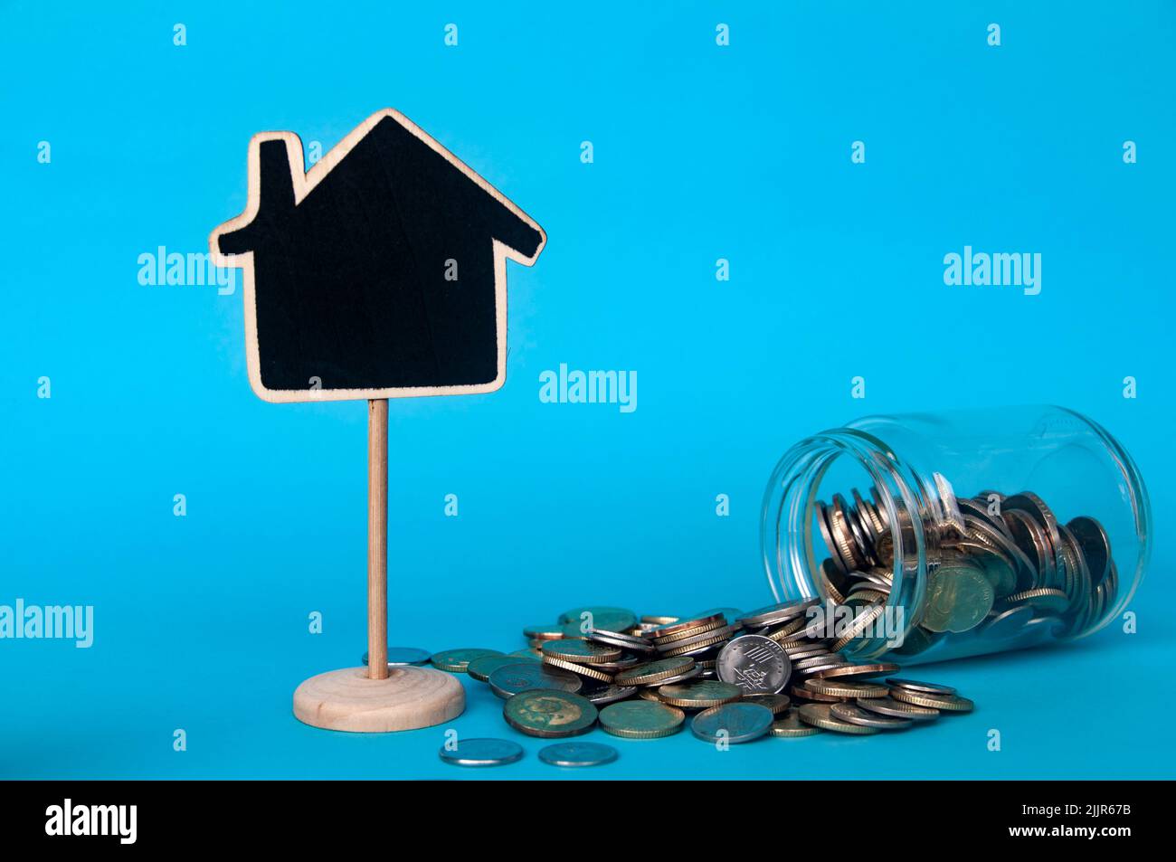 Monete d'oro sparse e modello vuoto casa con spazio personalizzabile per testo o idee . Copiare spazio e concetto di investimento Foto Stock