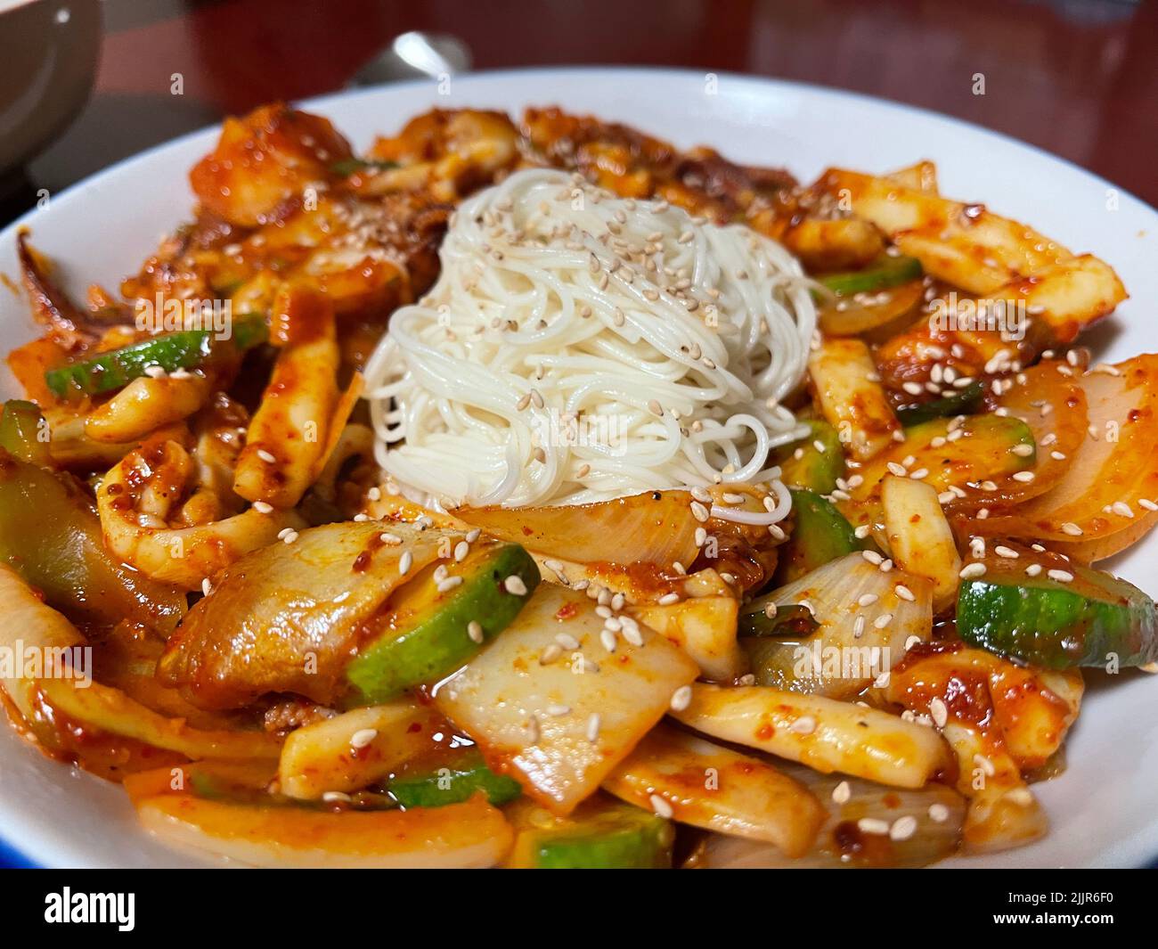 Un primo piano di calamari piccanti coreani mescolare friggere con tagliatelle nel mezzo Foto Stock