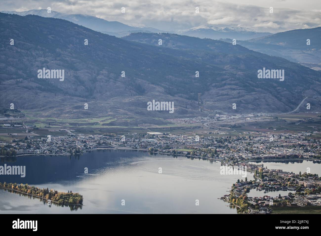 Una vista dall'alto di una città sulla riva di un lago contro una catena montuosa in una giornata nuvolosa Foto Stock
