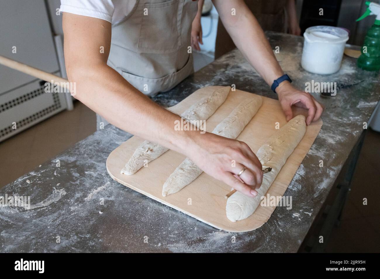 Il processo di produzione del pane tradizionale francese. Baguette, intagliando l'impasto. Vista frontale. Foto Stock